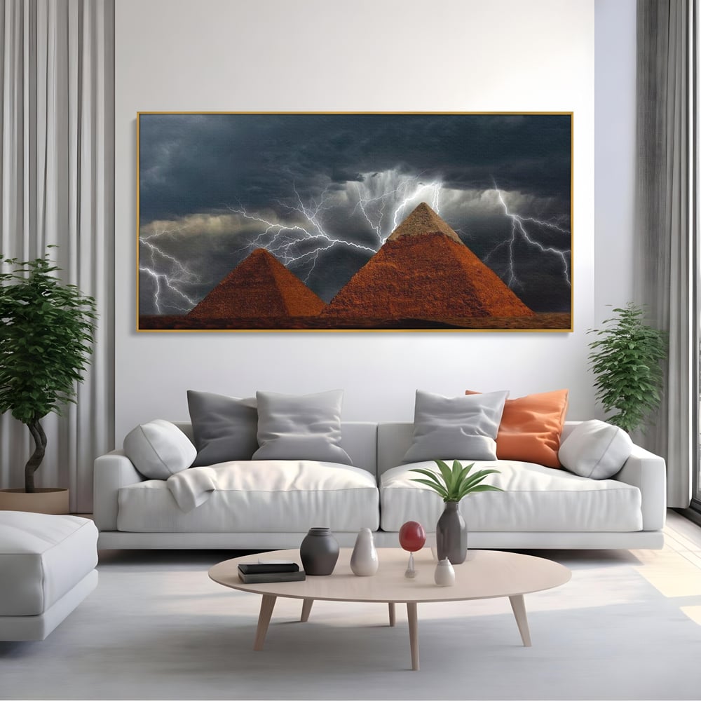 Tablou canvas cu ilustratie cu piramide si fulgere, in rama de aluminiu auriu, pe perete intr-un living